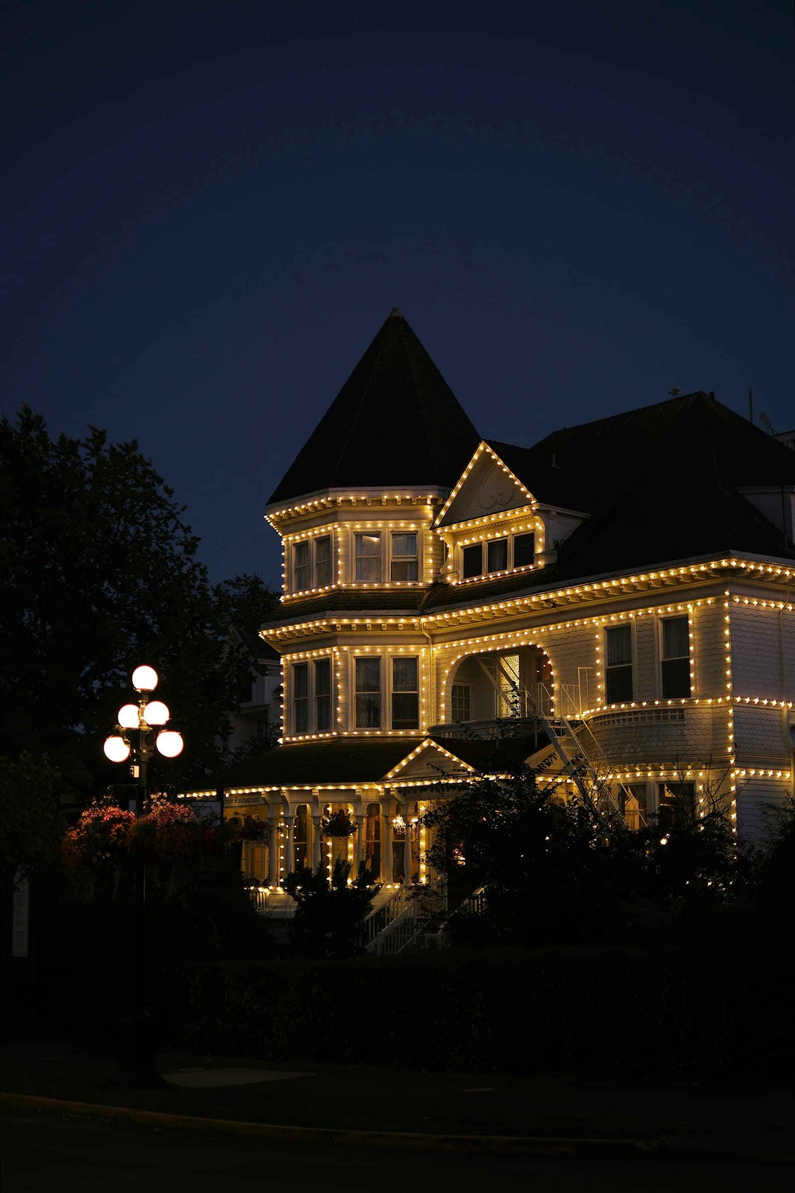 House roofline outlined in warm white holiday lights at dusk