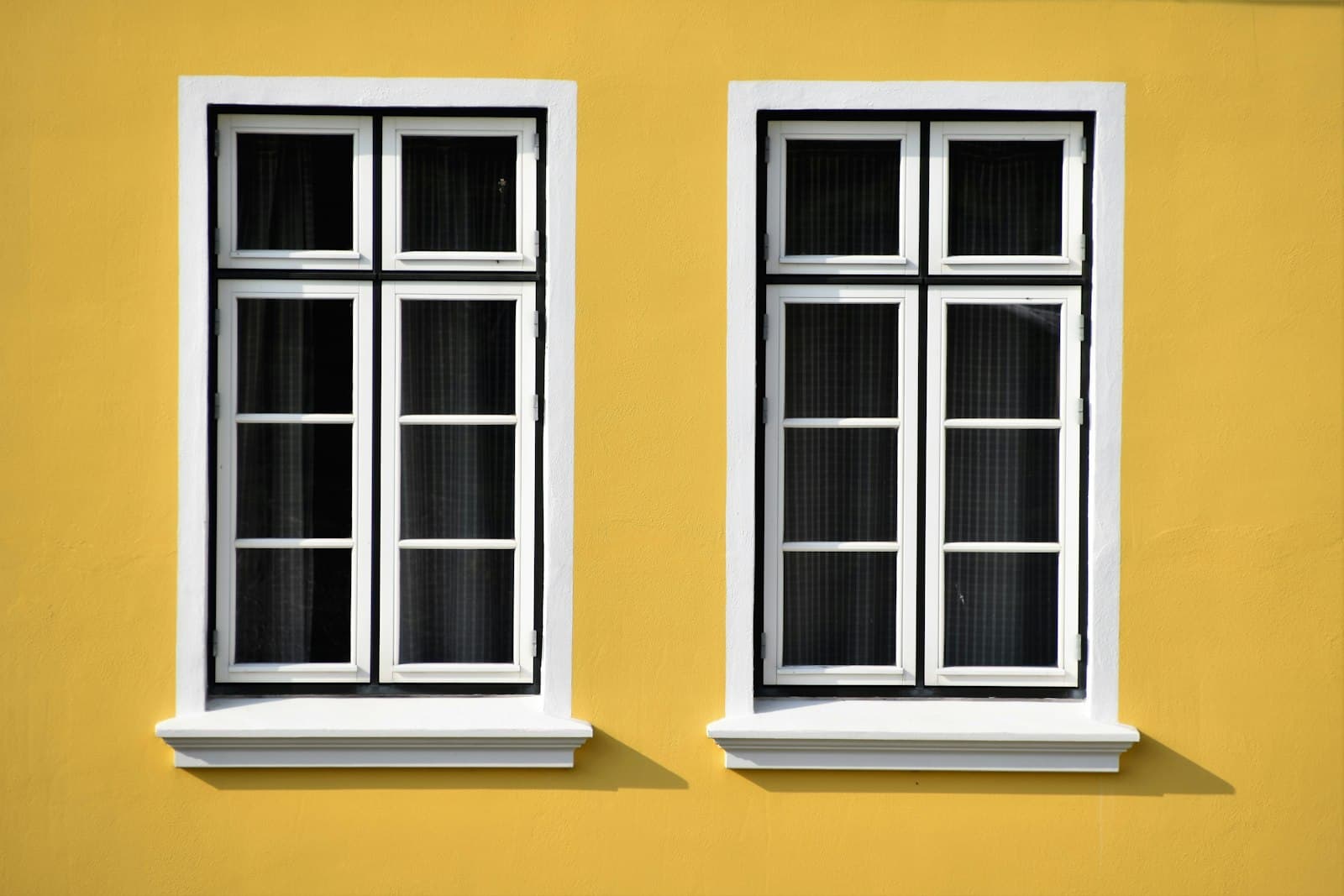 Two clean white-framed windows on a yellow house